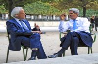 Two men in suits sitting on chairs outside