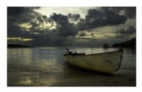 A boat is sitting on the beach under cloudy skies.