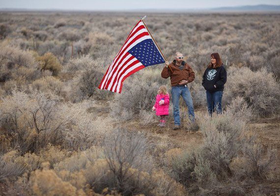 A man and woman holding an american flag in the middle of nowhere.