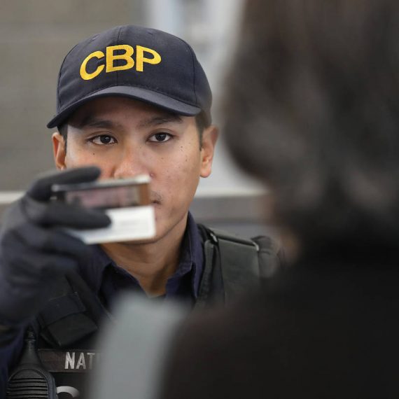 A cbp officer is holding a cell phone.